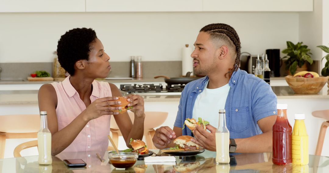 Diverse Couple Enjoying Burgers at Home Kitchen Table