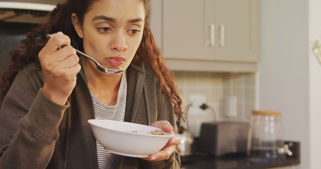 Young Woman Eating Breakfast Cereal in Modern Kitchen - Free Images, Stock Photos and Pictures on Pikwizard.com