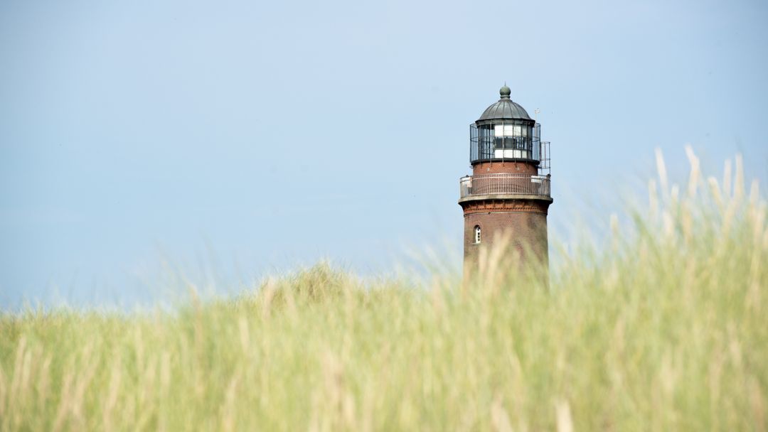 Historic Lighthouse Overlooking Grassy Dune on a Clear Day - Free Images, Stock Photos and Pictures on Pikwizard.com