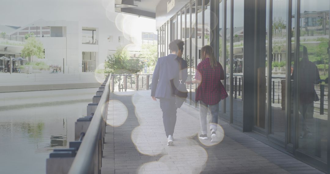 Colleagues Walking and Chatting by Waterside Office Complex