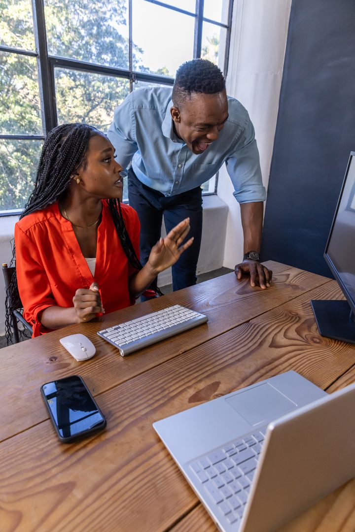 Coworkers Collaborating at Office Desk by Large Window