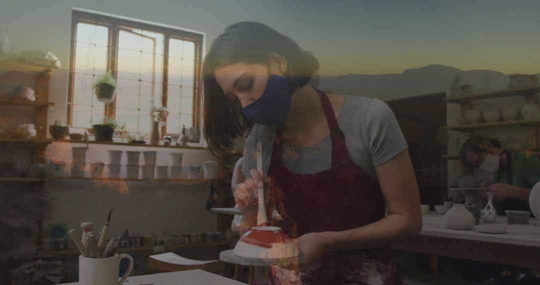 Artisan Brushing Glaze on Ceramic in Rustic Potter's Studio