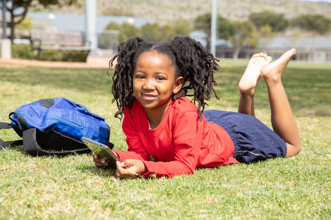 Young Girl Relaxing on Grass with Tablet at Park