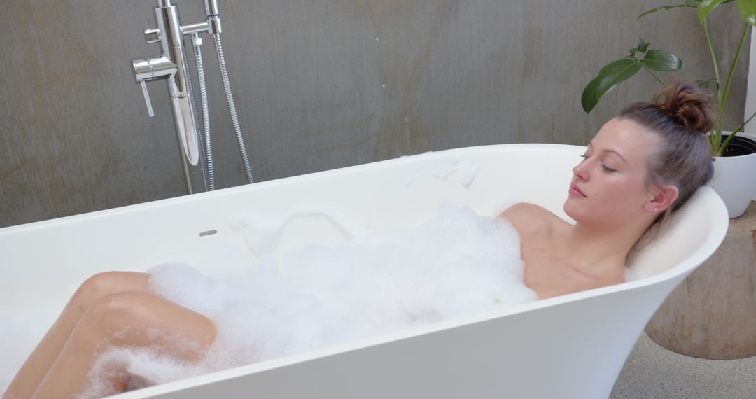 Woman Relaxing in Freestanding Bathtub With Foam Bubbles
