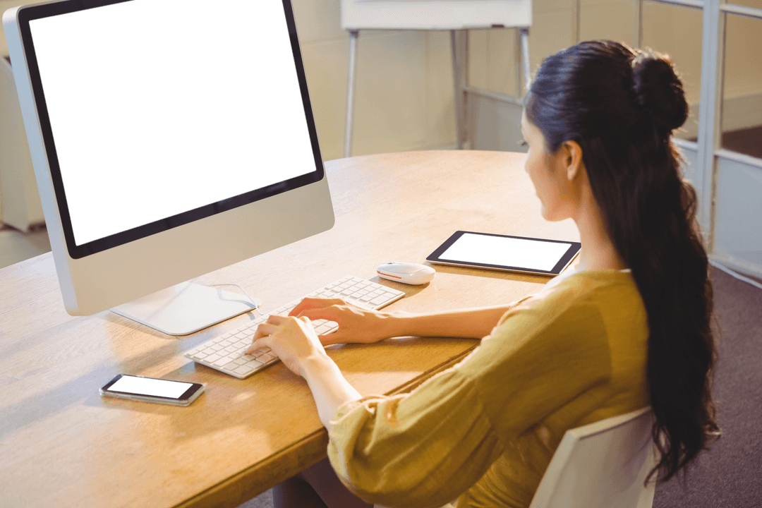 Businesswoman at Desk Working on Computer with Gadgets Visible
