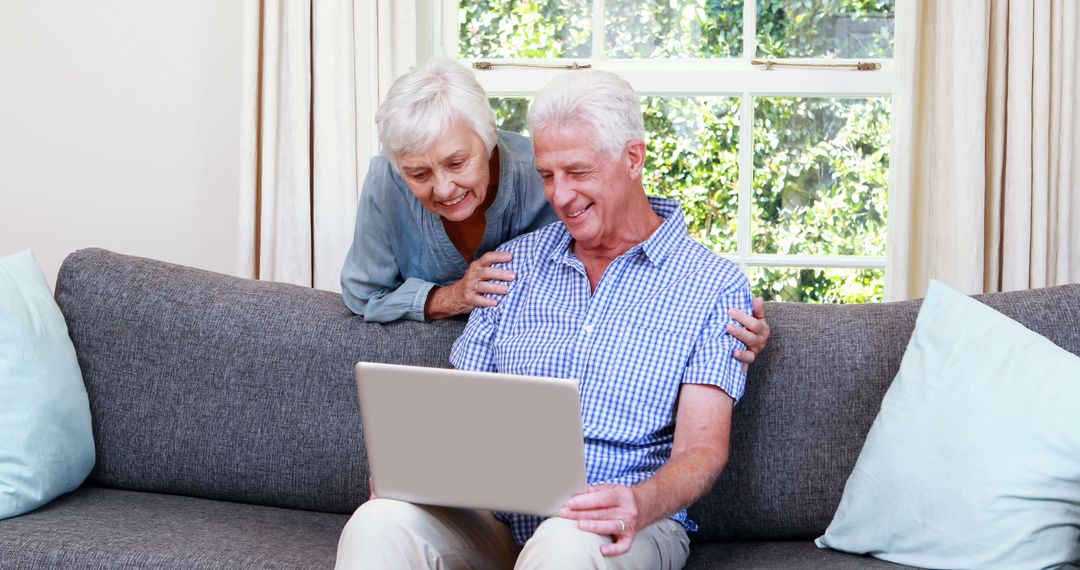 Happy Senior Couple Using Laptop on Couch - Free Images, Stock Photos and Pictures on Pikwizard.com