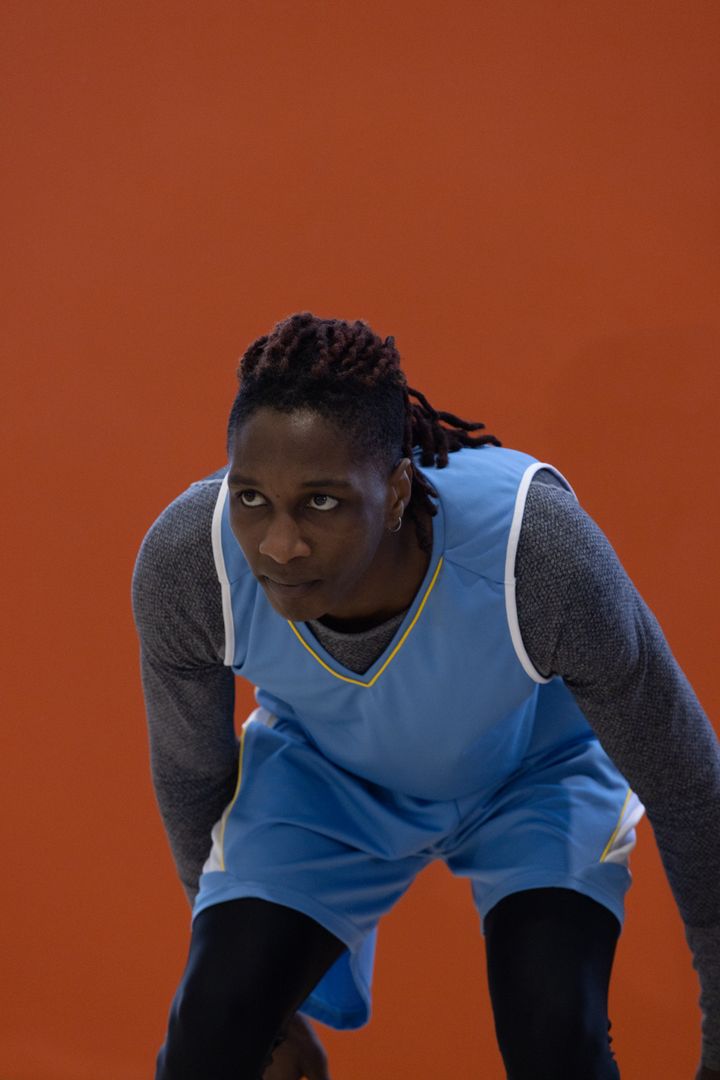 Determined Basketball Player in Action against Vibrant Orange Wall