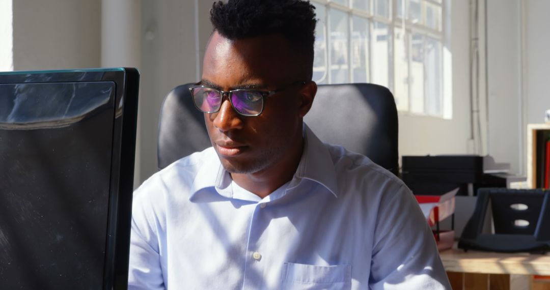 Focused Young Businessman Working on Desktop in Modern Office