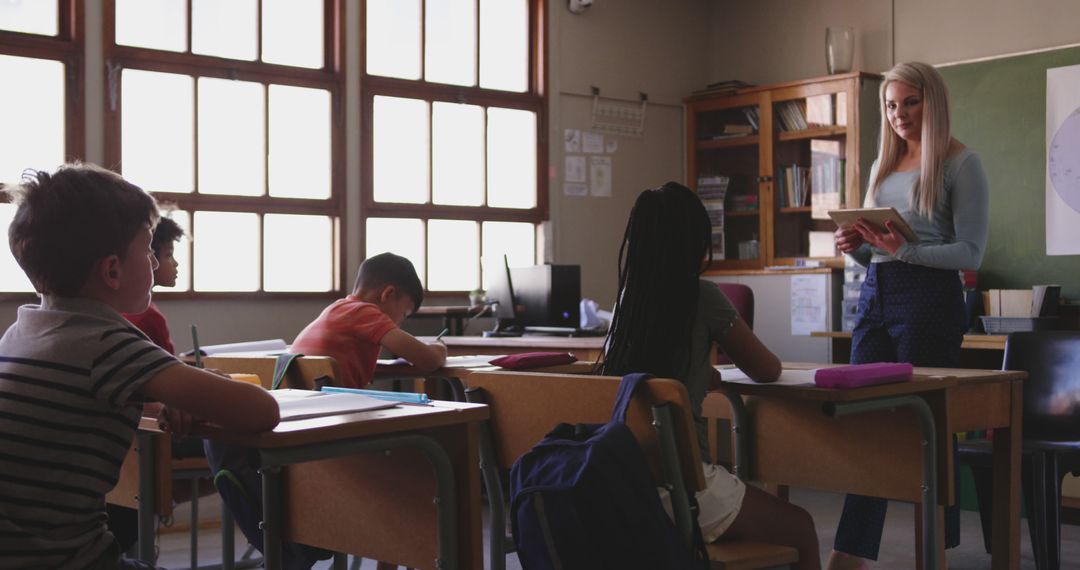 Teacher Using Tablet with Attentive Elementary Students in Classroom
