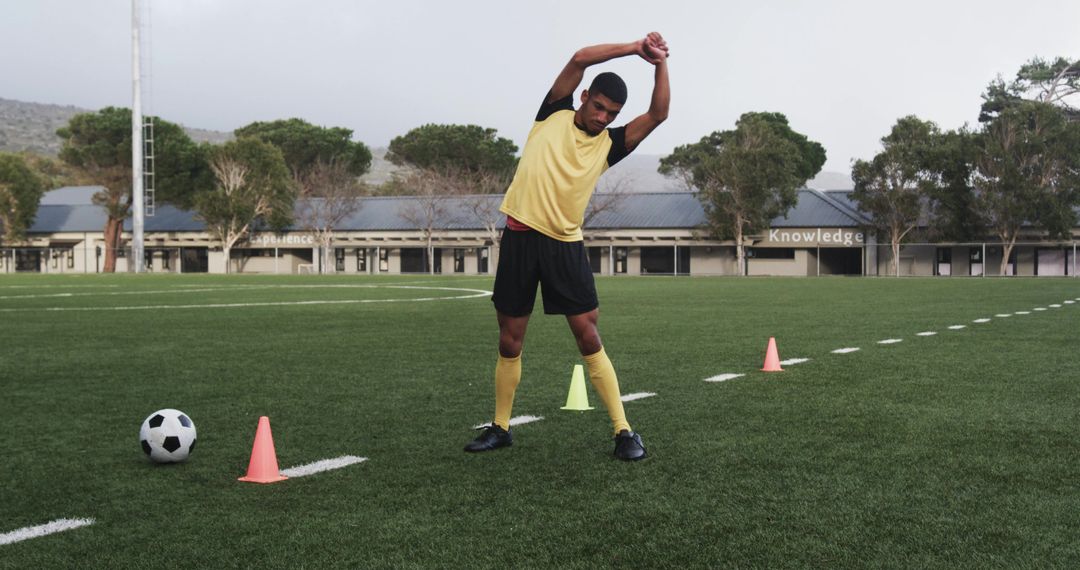 Soccer Player Stretching on Field Before Training Session