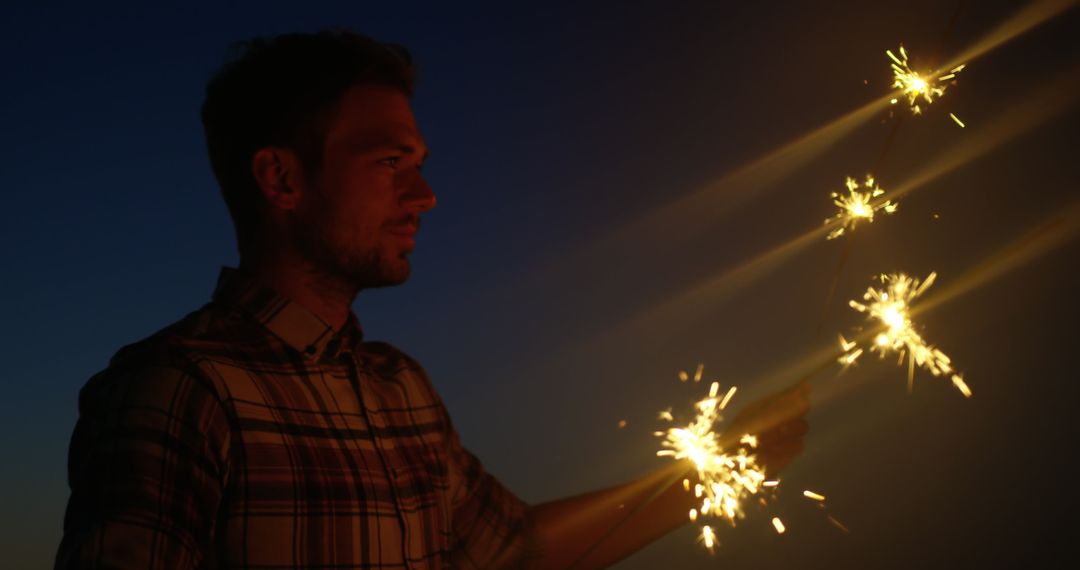 Man Holding Sparkler at Dusk on Beach