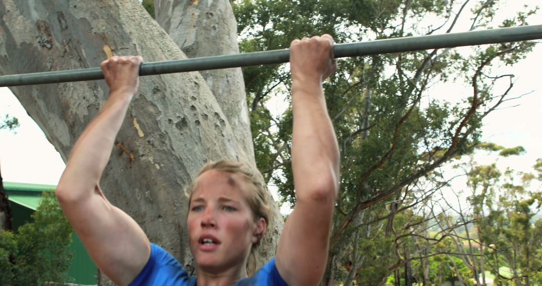 Woman Performing Pull-Ups Outdoors with Determined Expression - Free Images, Stock Photos and Pictures on Pikwizard.com