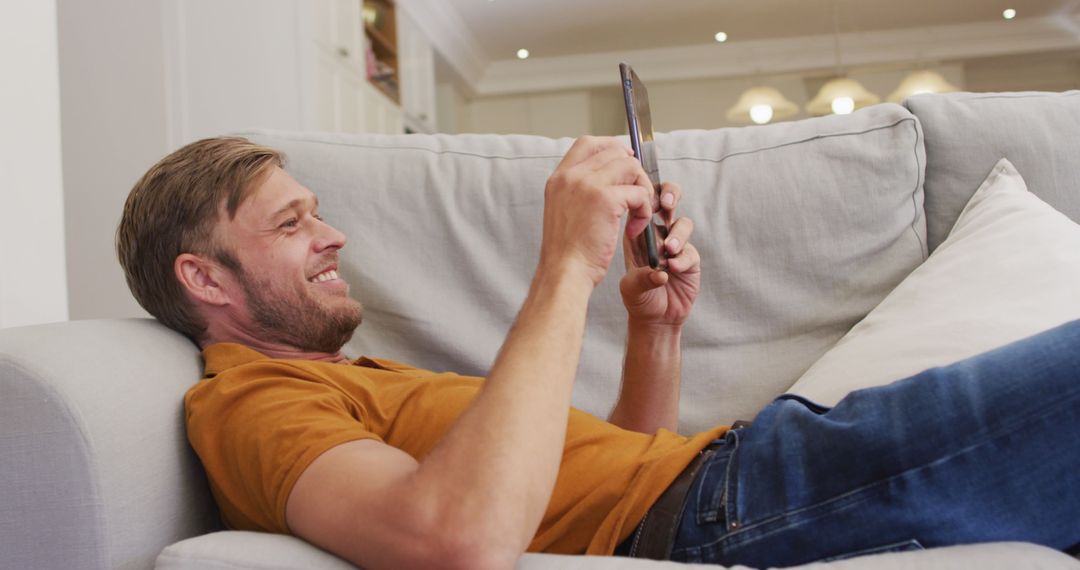Smiling Man Relaxing on Couch Using Digital Tablet - Free Images, Stock Photos and Pictures on Pikwizard.com