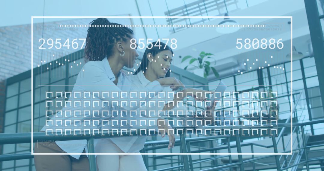 Women Collaborating on Digital Project in Modern Office Atrium