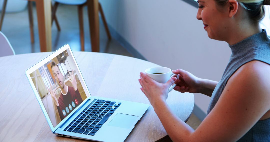 Woman Video Conferencing on Laptop While Enjoying Coffee at Home - Free Images, Stock Photos and Pictures on Pikwizard.com