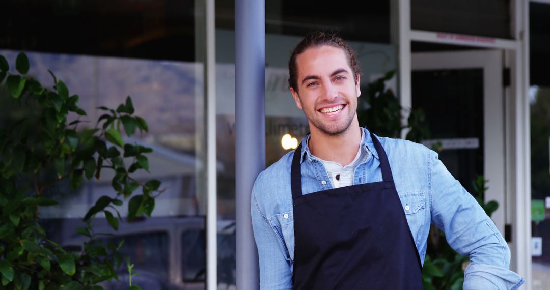 Smiling Young Male Barista in Apron Standing Outdoors - Free Images, Stock Photos and Pictures on Pikwizard.com