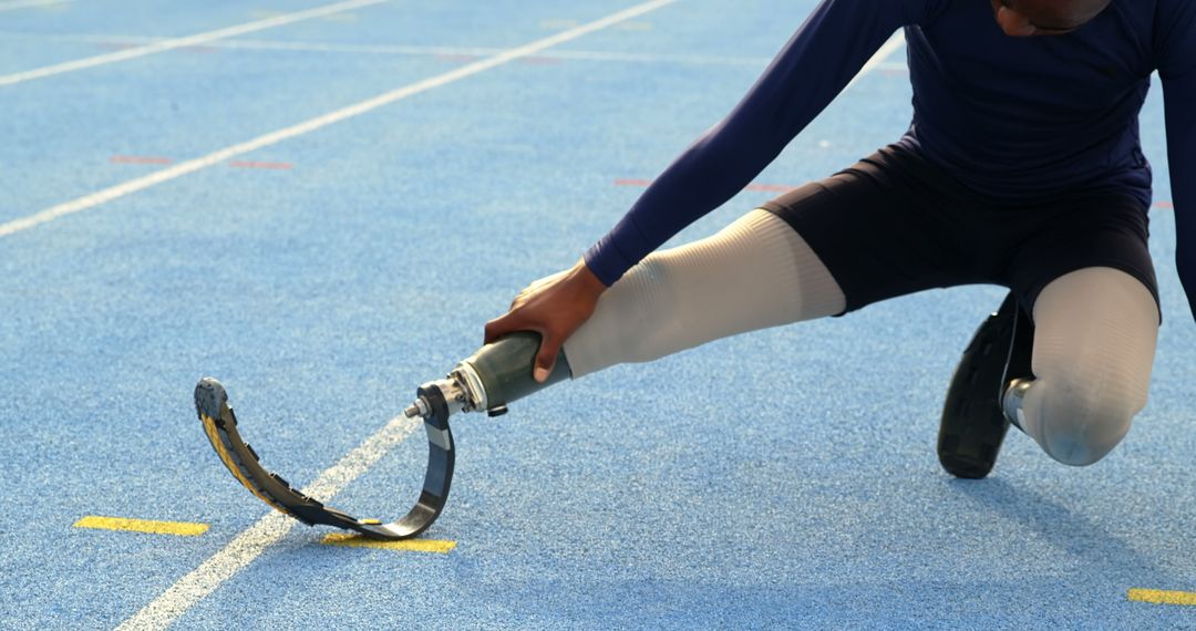 Athlete Preparing Prosthetic Leg for Track Running on Blue Track Surface - Free Images, Stock Photos and Pictures on Pikwizard.com