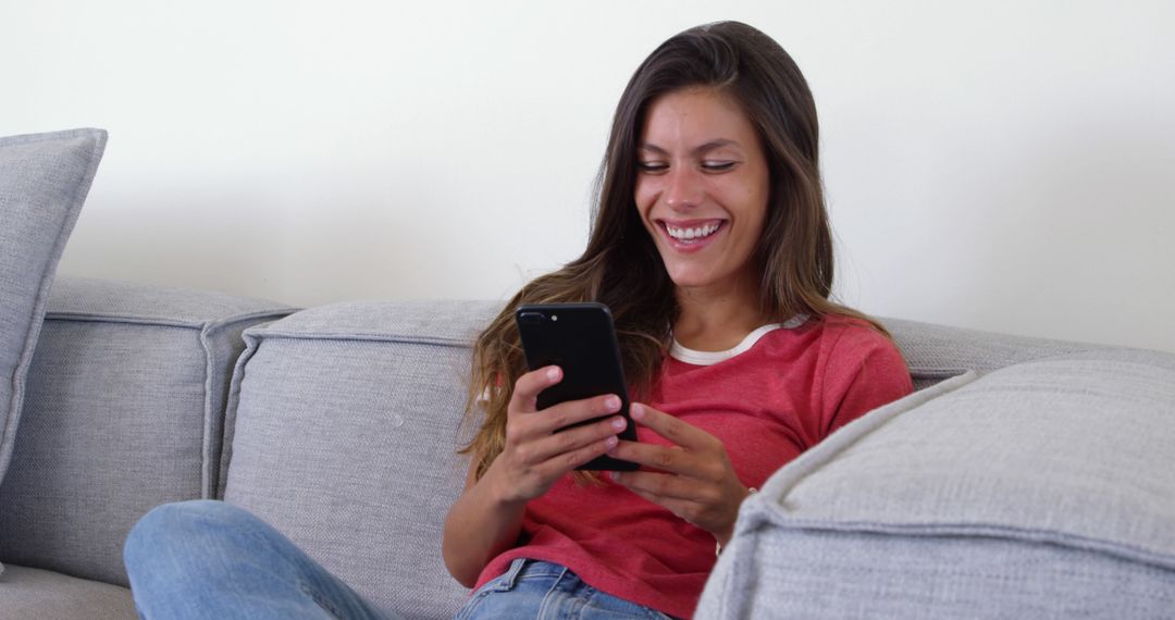 Woman Smiling While Using Smartphone on Couch - Free Images, Stock Photos and Pictures on Pikwizard.com