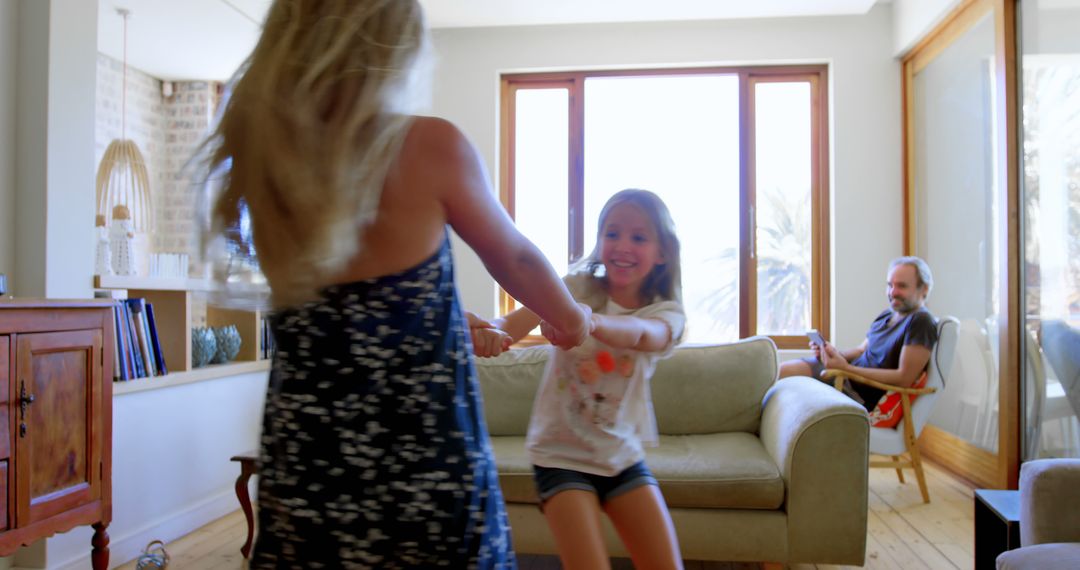 Mother and Daughter Dancing in Living Room with Relaxed Father in Background - Free Images, Stock Photos and Pictures on Pikwizard.com