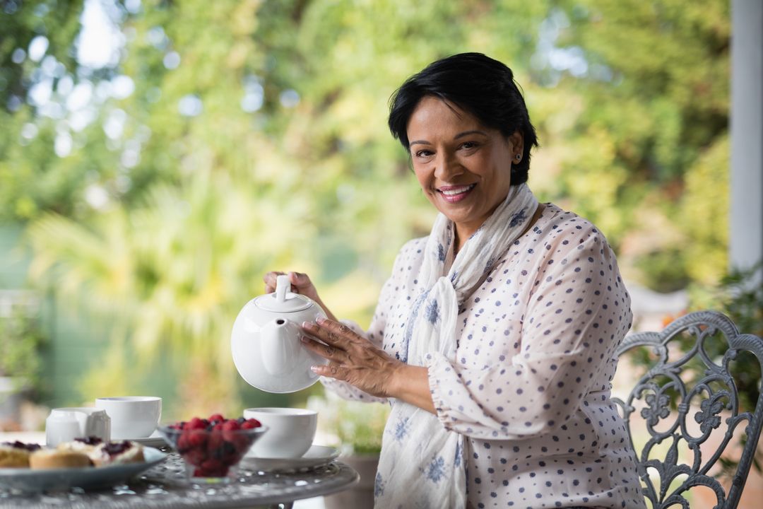 Portrait of smiling mature woman pouring tea in cup - Free Images, Stock Photos and Pictures on Pikwizard.com