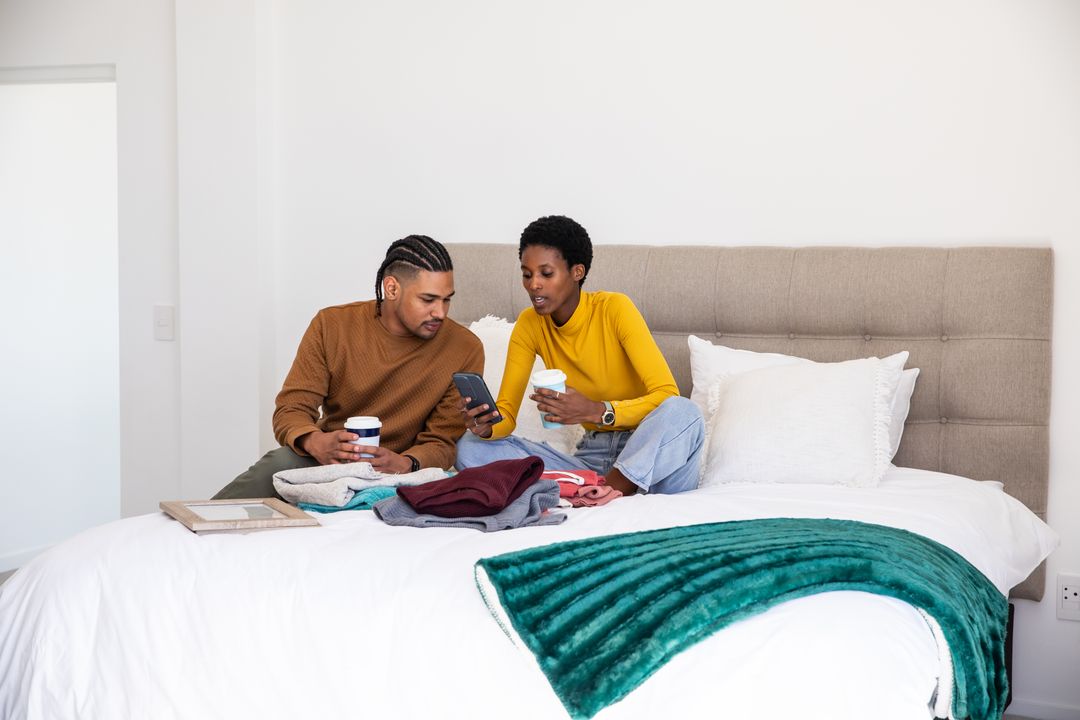 Couple Enjoying Coffee While Sorting Clothes on Bed