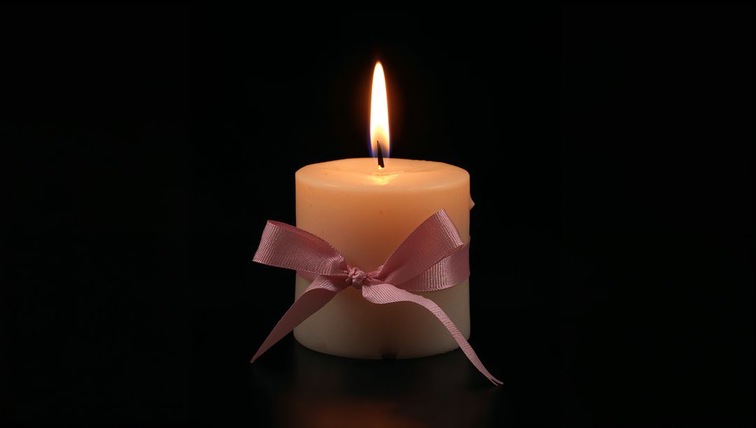 Ivory Pillar Candle with Pink Ribbon on Reflective Surface