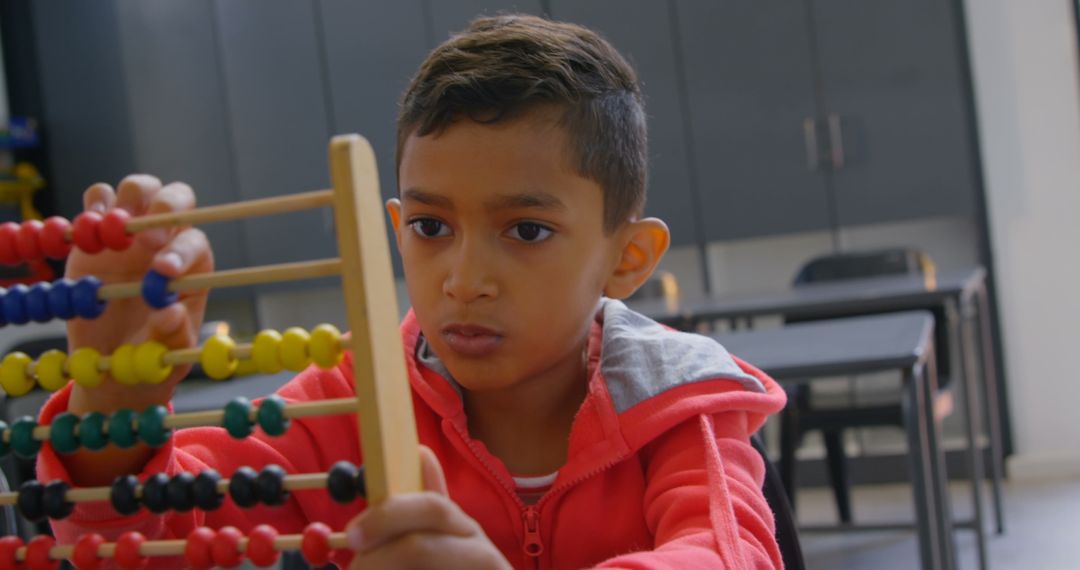 Focused Young Schoolboy Learning Math with Abacus in Classroom