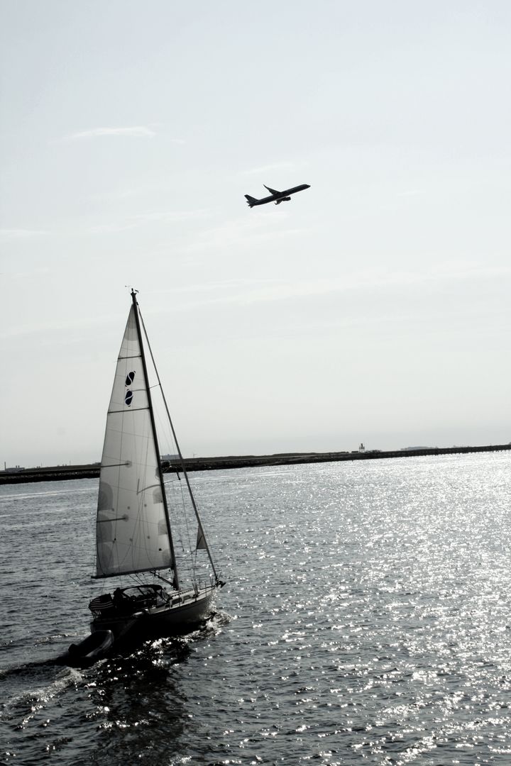 Sailboat and Airplane on Ocean Water Under Clear Sky - Free Images, Stock Photos and Pictures on Pikwizard.com