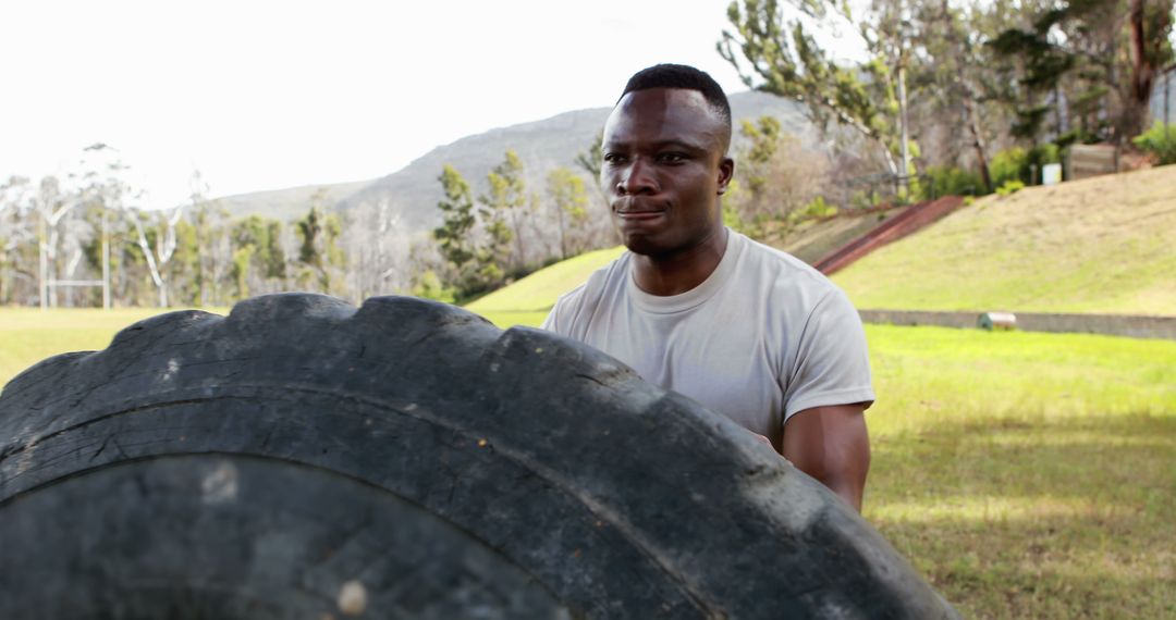 Man flipping large tire during outdoor fitness training in park - Free Images, Stock Photos and Pictures on Pikwizard.com