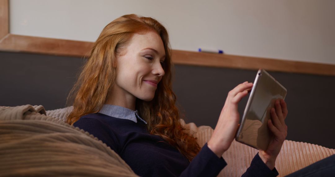 Smiling woman with red hair using tablet at home - Free Images, Stock Photos and Pictures on Pikwizard.com