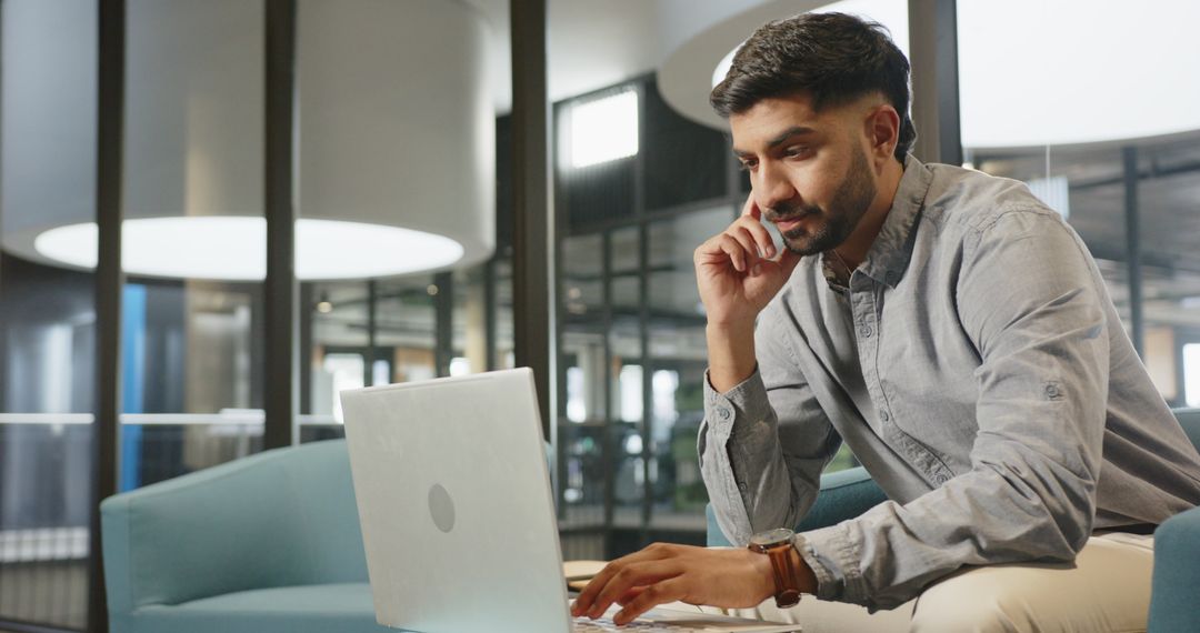 Young Professional Using Laptop in Modern Office Lounge