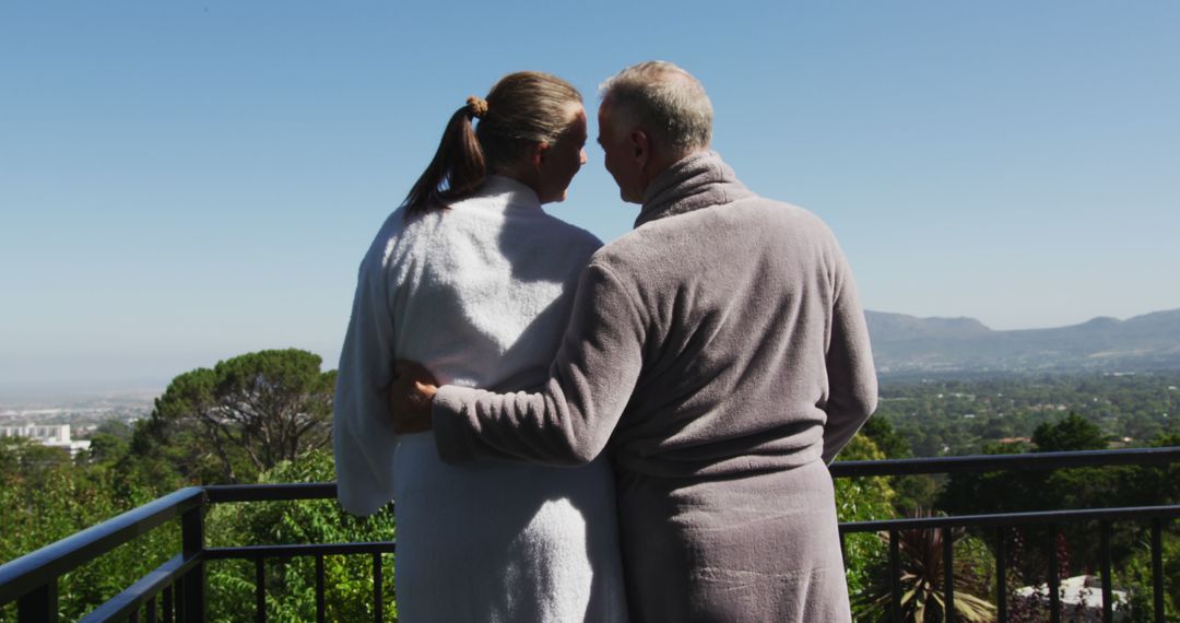 Rear view of caucasian senior couple in bathrobes embracing each other in the balcony at home - Free Images, Stock Photos and Pictures on Pikwizard.com