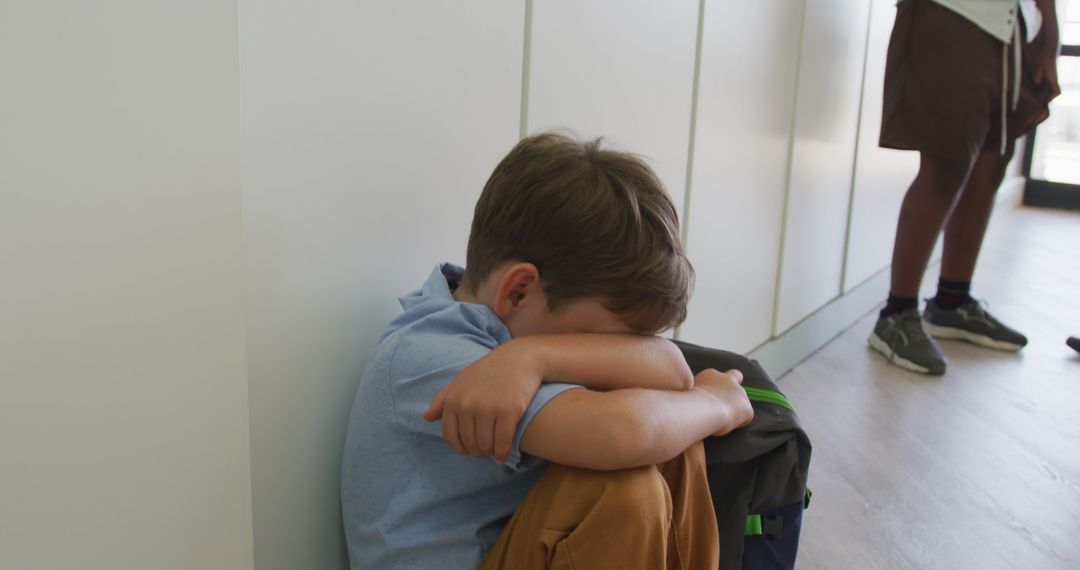 Image of sad caucasian boy sitting at school corridor, covering head with hands - Free Images, Stock Photos and Pictures on Pikwizard.com