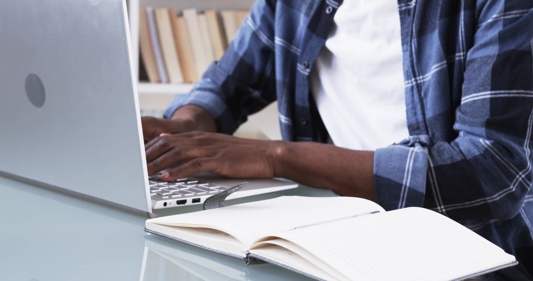 Man Working on Laptop While Notetaking in Home Workspace