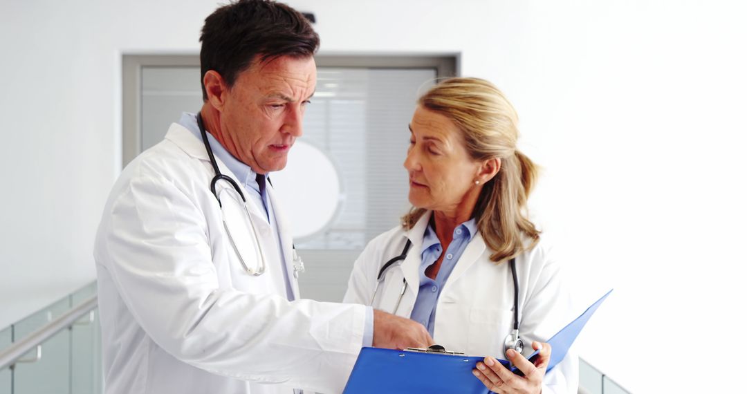 Two Doctors Discussing Patients' Records in Hospital Corridor - Free Images, Stock Photos and Pictures on Pikwizard.com