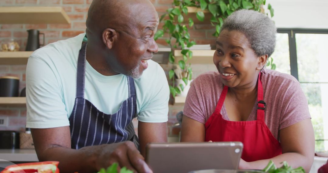 Smiling Senior Couple Cooking and Enjoying Tablet in Kitchen