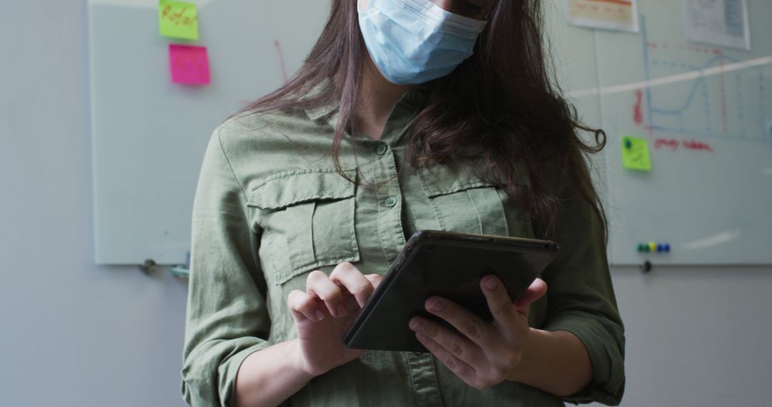 Businesswoman Using Tablet While Wearing Face Mask in Office - Free Images, Stock Photos and Pictures on Pikwizard.com