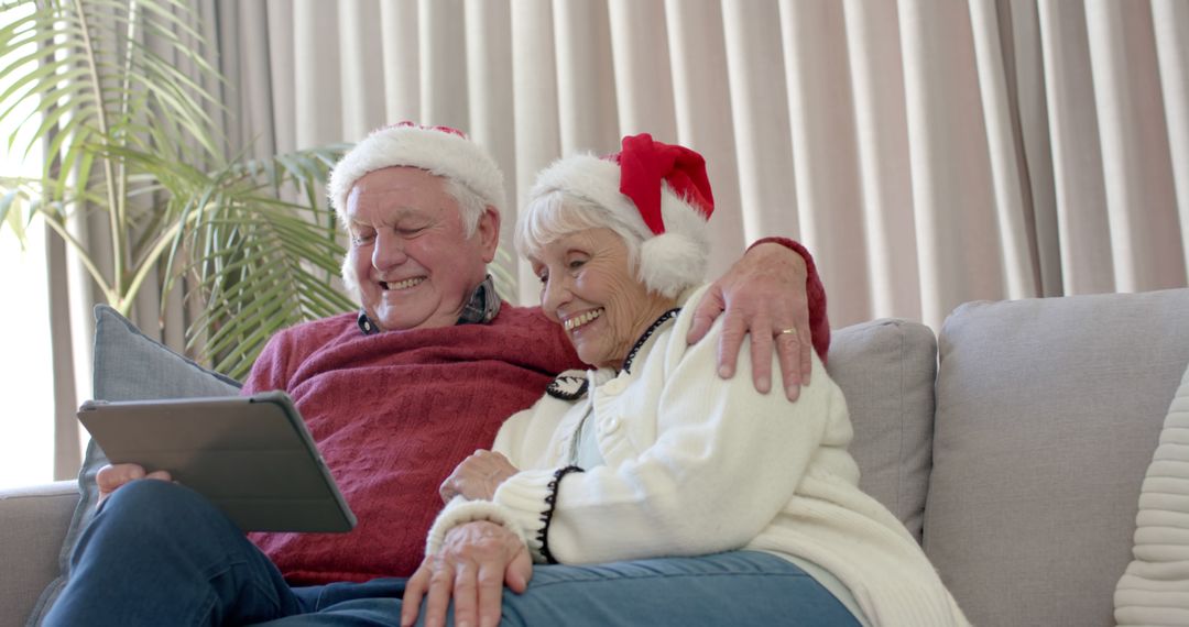 Happy Elderly Couple Watching Tablet at Christmas - Free Images, Stock Photos and Pictures on Pikwizard.com