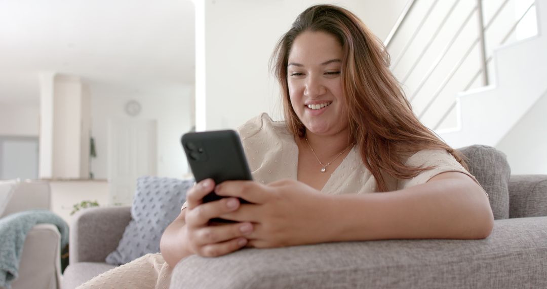 Smiling Plus Size Woman Relaxing with Smartphone on Sofa