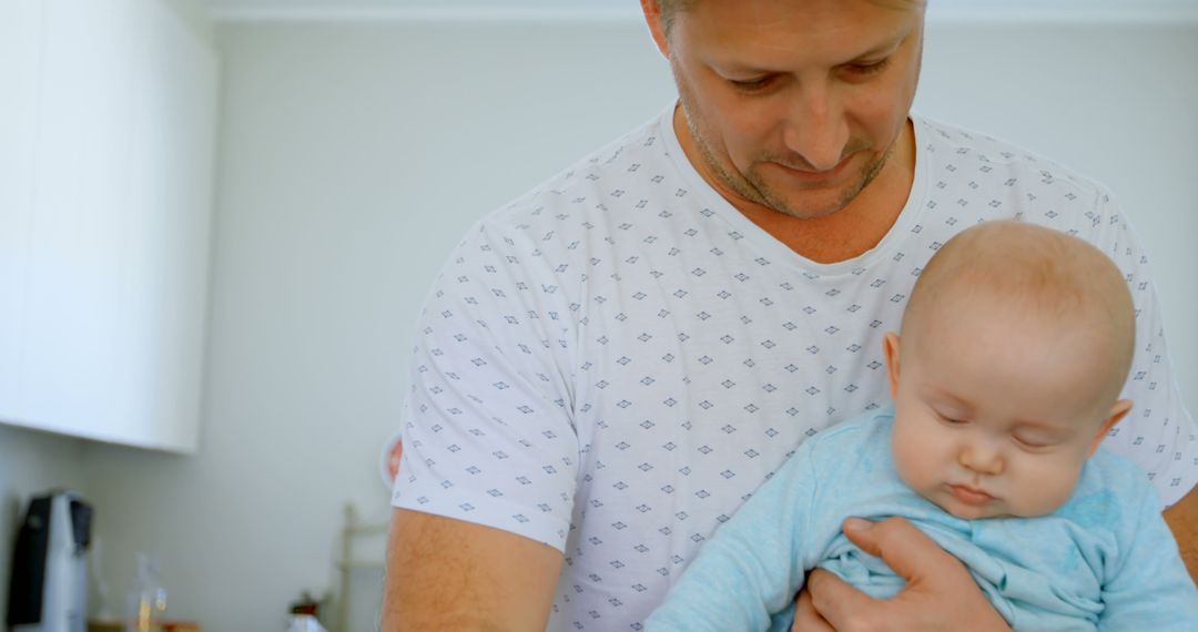 Father Holding Sleeping Baby in Bright Home Environment - Free Images, Stock Photos and Pictures on Pikwizard.com