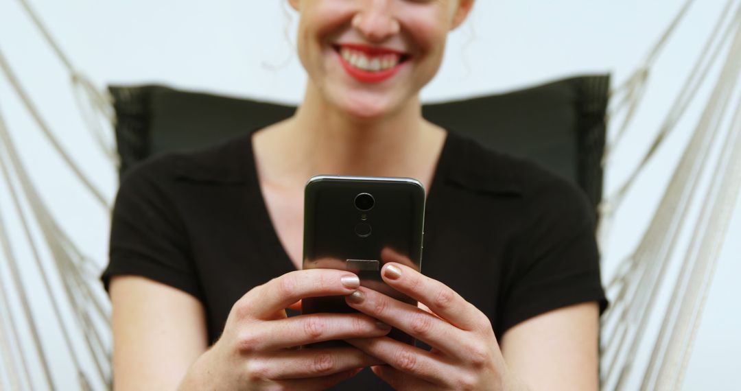 Woman Smiling Using Smartphone While Relaxing in Hammock - Free Images, Stock Photos and Pictures on Pikwizard.com