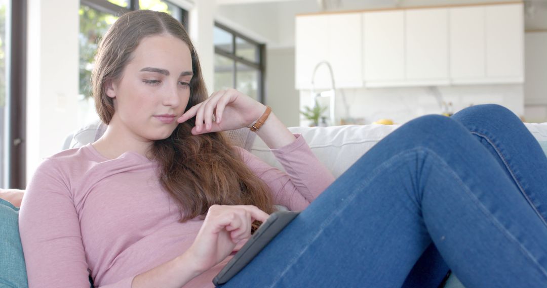 Young Woman Relaxing on Couch Using Tablet - Free Images, Stock Photos and Pictures on Pikwizard.com