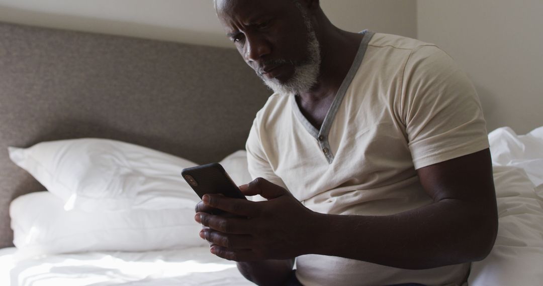 Senior man using smartphone while sitting on bed - Free Images, Stock Photos and Pictures on Pikwizard.com