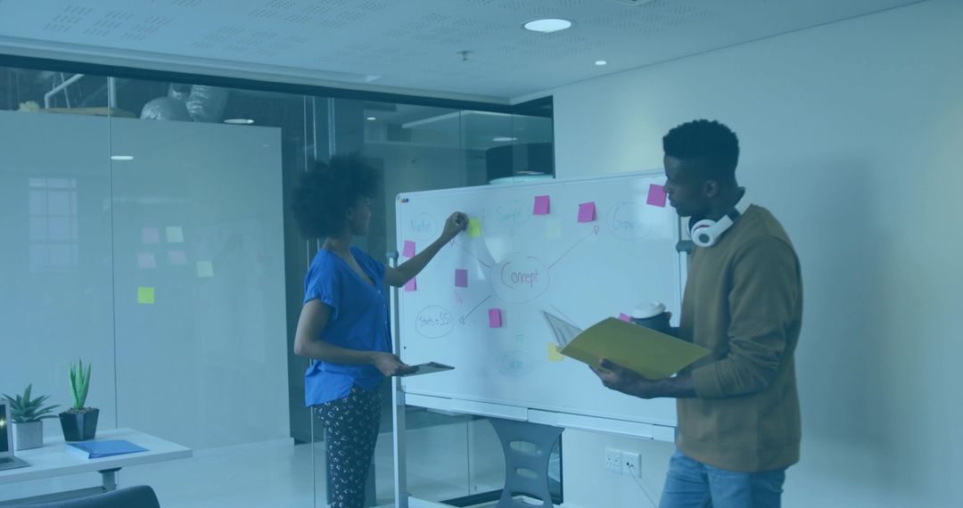 Team brainstorming at whiteboard placing sticky notes and mapping ideas in office workshop