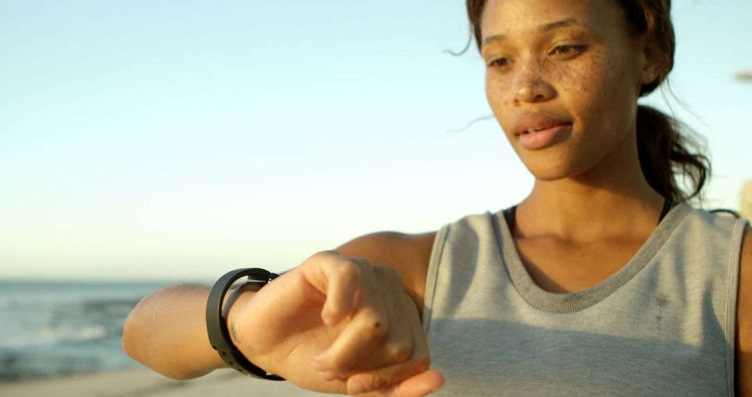 Sporty Woman Checking Smartwatch on Beach at Sunset - Free Images, Stock Photos and Pictures on Pikwizard.com