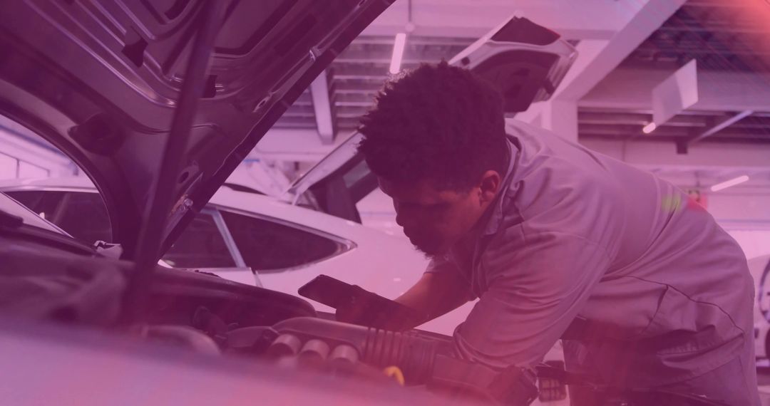 Mechanic inspecting engine bay with smartphone under raised hood in garage with purple lighting