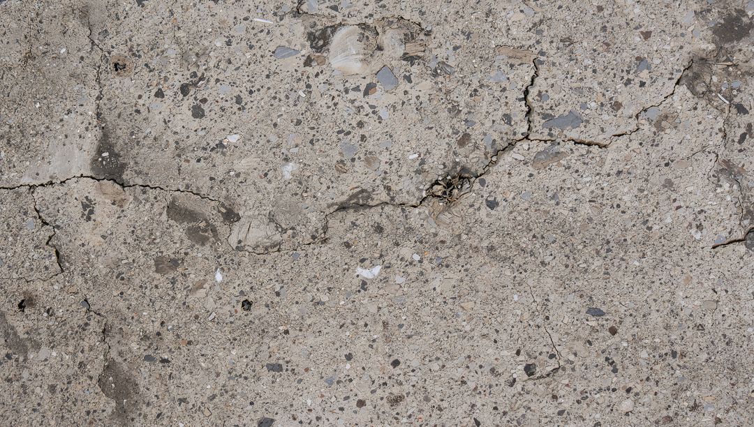 Weathered Concrete Slab with Branching Fissures and Exposed Aggregate Texture Close-up