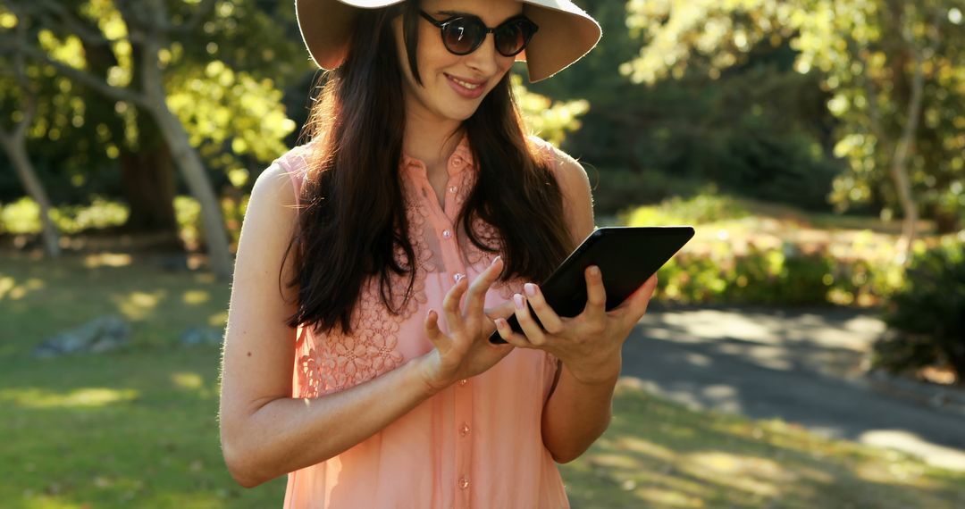 Young Woman with Hat and Sunglasses Using Tablet Outdoors - Free Images, Stock Photos and Pictures on Pikwizard.com