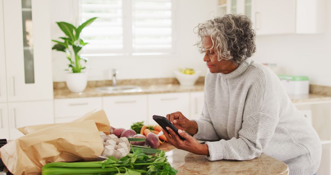 Senior Woman Using Smartphone in Healthy Kitchen - Free Images, Stock Photos and Pictures on Pikwizard.com