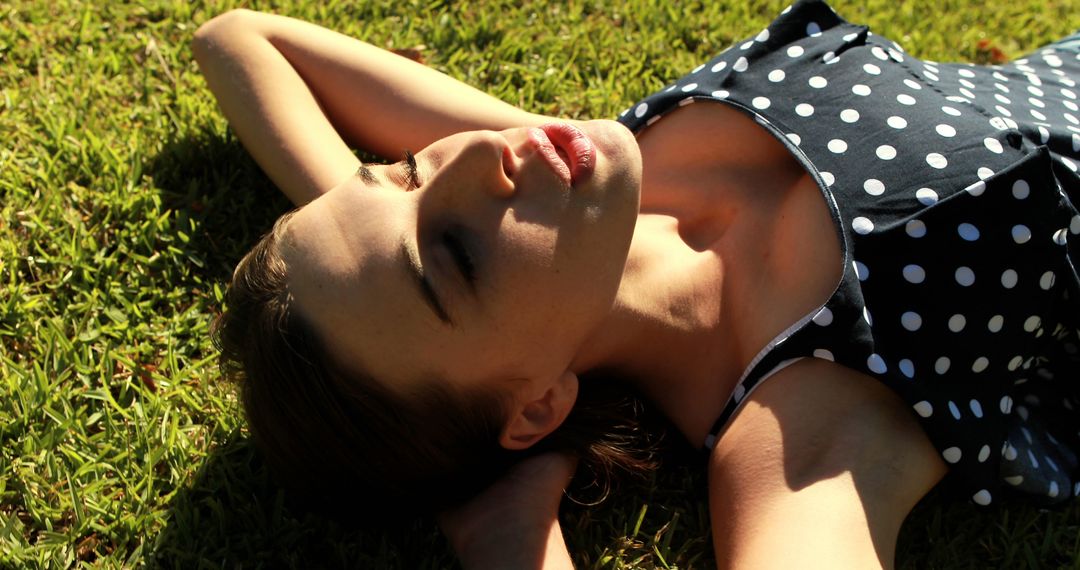 Young Woman Relaxing on Grass in Polka Dot Dress - Free Images, Stock Photos and Pictures on Pikwizard.com